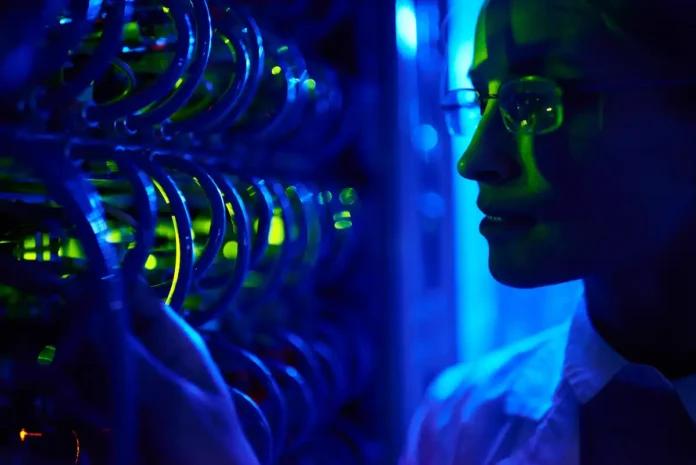Ricercatrice accanto a un computer quantistico con luci blu e verdi – quantum computing